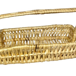 May include: A rectangular woven basket made of light tan natural reeds, featuring an open-top design with a single arched handle extending from the center of the long sides. The basket has a sturdy base and a consistent, repeating weave pattern.
