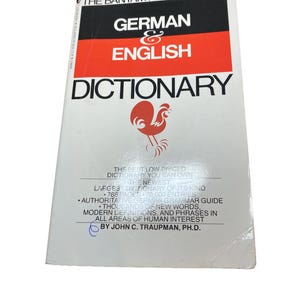 Op de afbeelding: Een paperback woordenboek Duits & Engels van The Bantam New College. De witte omslag heeft zwarte en rode tekst en een illustratie van een haan. Het bevat 768 pagina's en 70.000 items, met een grammatica gids.