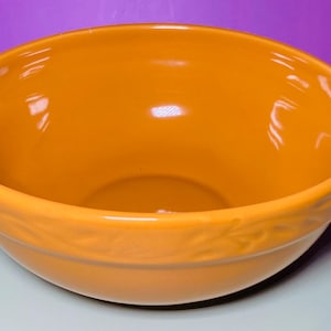 May include: A large, orange ceramic mixing bowl with a decorative rim.