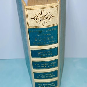 May include: A vintage Reader's Digest Condensed Books volume. The spine is light blue with gold lettering and a decorative floral design. Titles include "The Final Diagnosis" and "Strangers in the Forest."