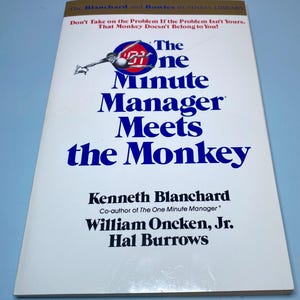 以下が含まれることがあります： 「The One Minute Manager Meets the Monkey」というタイトルのハードカバー本。表紙には、青と白の文字と、人物と猿のグラフィックが描かれています。著者はケネス・ブランチャード、ウィリアム・オンケン・ジュニア、ハル・バローズです。