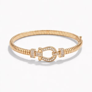 May include: A gold-toned bracelet featuring a flexible, ribbed band and a central horseshoe-shaped clasp. The clasp is embellished with small, clear, sparkling stones set along its surface, creating a refined and polished appearance.