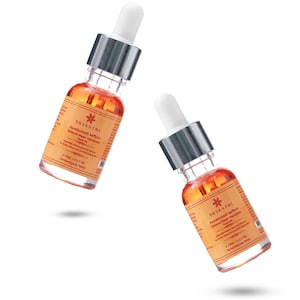 May include: Two glass bottles of face oil with white droppers and silver collars. The bottles are filled with an orange liquid and have labels with text and a floral design. The bottles are labeled "SHYANTHI". Each bottle contains 15ml or 0.5 fl oz.