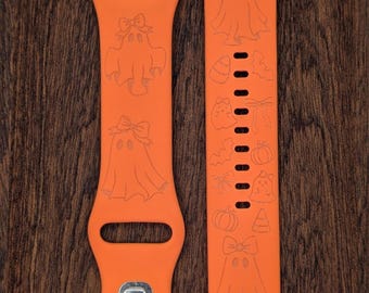 Può includere: Due cinturini arancioni per orologi con disegni a tema Halloween. Uno presenta figure di fantasmi con fiocchi, l'altro ha varie icone di Halloween come zucche e caramelle. I cinturini sono realizzati in materiale flessibile.