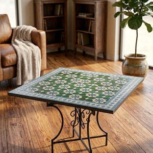 Peut inclure: Une table carrée dotée d'un plateau en mosaïque avec un motif répétitif de cercles verts et d'accents en forme d'étoile bleue, bordé par un cadre géométrique bleu clair et blanc, reposant sur une base en métal noir avec des volutes décoratives.