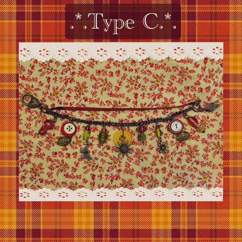 May include: A decorative charm bracelet with various charms, including buttons, leaves, and a sunburst. The bracelet is displayed on a floral fabric background with the text "Type C." at the top. The background is framed with a white lace trim.