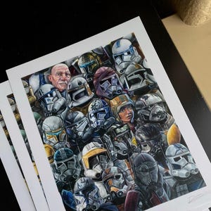 May include: A detailed print featuring a collage of Star Wars clone trooper helmets and characters. The artwork showcases a variety of helmet designs in shades of white, grey, blue, orange, and yellow, with a few faces visible. The print is on white paper.