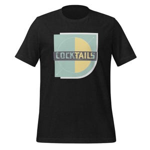 May include: Black t-shirt featuring a graphic of a teal and yellow circle with the word "COCKTAILS" in a vintage font.