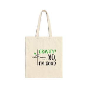 Puede incluir: Una bolsa de tela beige con una estrella verde y texto negro que dice "GRAVITY? NO, I'M GOOD".