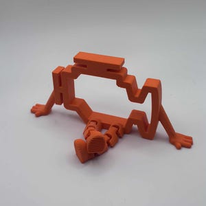 Puede incluir: Una escultura geométrica naranja de una persona sentada. La figura tiene un diseño en bloques con brazos, piernas y una cabeza. La escultura está hecha de un material sólido y está colocada sobre un fondo blanco.