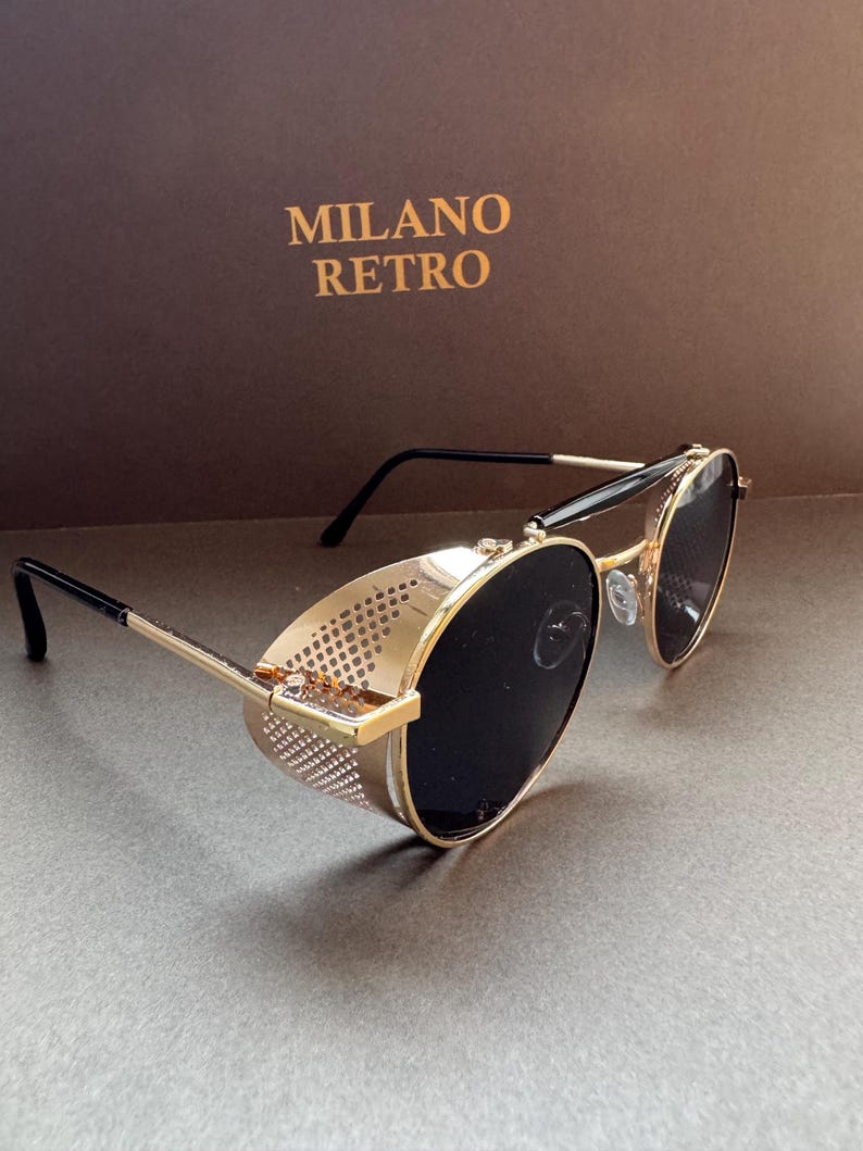 May include: Gold-rimmed sunglasses with black lenses and side shields. The sunglasses have a retro design, with the text "MILANO RETRO" in gold on the background.