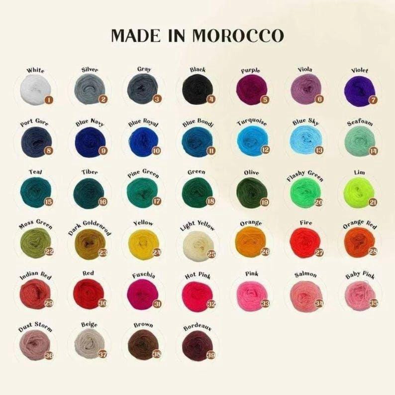May include: A color chart of yarn balls, each labeled with a color name and number. Colors range from white to black, with shades of blue, green, yellow, red, and pink. The text "MADE IN MOROCCO" is at the top.