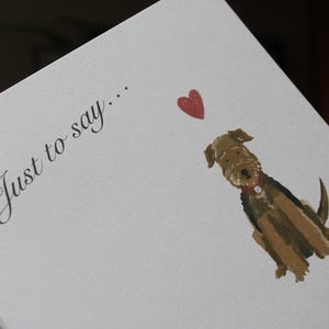 K&ouml;nnte beinhalten: Wei&szlig;e Karte mit dem Text "Just to say..." in Schreibschrift. Eine Aquarellillustration eines braun-schwarzen Hundes mit rotem Halsband und rotem Herz.