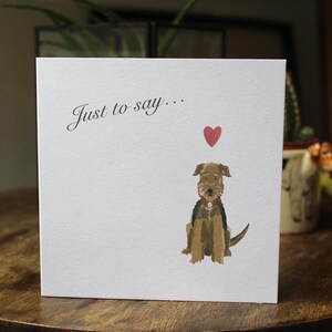 K&ouml;nnte beinhalten: Wei&szlig;e Gru&szlig;karte mit dem Text "Just to say..." und einer Aquarellillustration eines Hundes und eines roten Herzens. Der Hund ist braun und schwarz mit rotem Halsband.