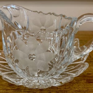 vintage heavy clear cut glass creamer with saucer. etched and frosted floral design.