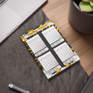 Könnte beinhalten: Ein Notizblock zur Leseverfolgung mit einem Design im Comic-Stil. Der Notizblock hat ein schwarz-weißes Raster zur Verfolgung des Lesefortschritts, mit den Worten "Reading Tracker" oben. Der Rand ist gelb und schwarz.