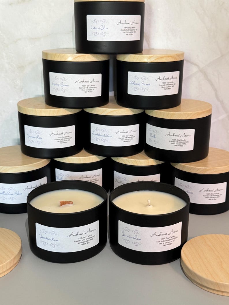 May include: A collection of ten black soy candles with wooden lids. The candles are arranged in a pyramid shape. The candles are labeled with different scents, including "Citrus Bliss", "Spring Breeze", "Relaxing Sunset", "Jasmine Rose", "Vanilla", and "Sandlewood Rose".