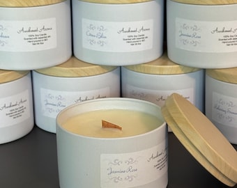 May include: A close-up of a white candle with a wooden lid. The candle is labeled "Awakened Aroma" and "Jasmine Rose". The candle is surrounded by other candles with various scents.