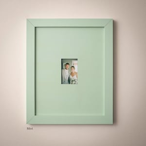 A framed photograph of a couple, likely a bride and groom, is displayed on a light green wall.