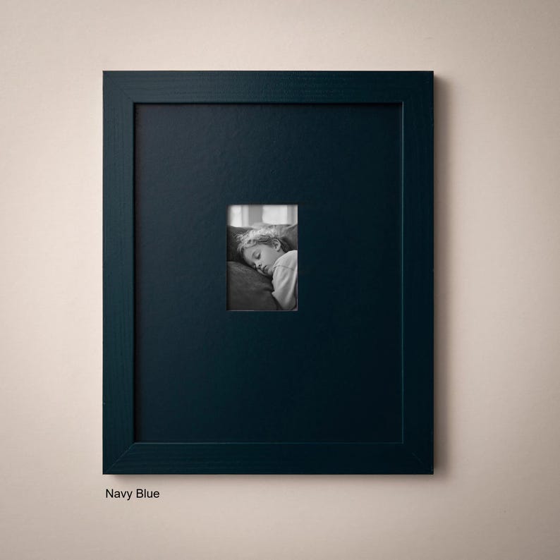 A black framed picture of a person sleeping is hanging on a light-colored wall.