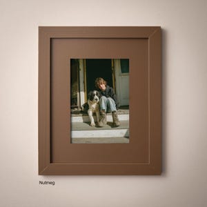 A framed photograph of a person sitting on a porch with a dog, both looking at the camera.