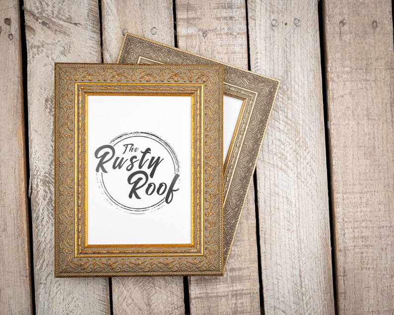 May include: Two gold picture frames with ornate detailing, the top frame is slightly offset from the bottom frame. The bottom frame has a white mat and a black and white logo that says "The Rusty Roof".