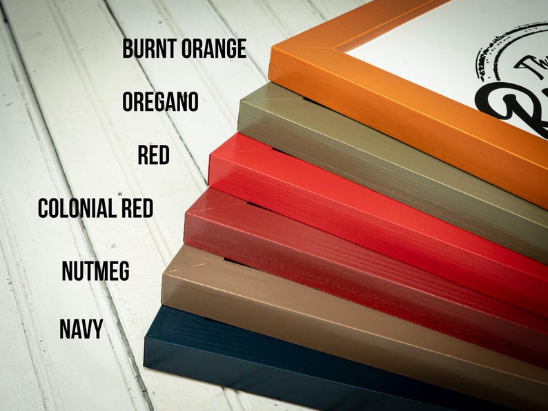 May include: A stack of picture frames in various colors, including burnt orange, oregano, red, colonial red, nutmeg, and navy. The frames are angled, showcasing their different hues and textures. The text on the left indicates the color names.