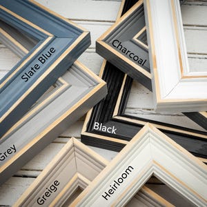 a pile of framed pictures sitting on top of a wooden floor