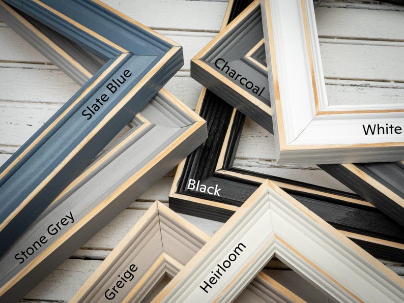 a pile of framed pictures sitting on top of a wooden floor
