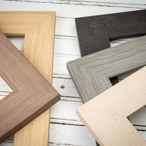 May include: Four different picture frames made of wood. The frames are in various shades of brown, gray, and beige. The frames are arranged in a way that shows the different colors and textures of the wood.