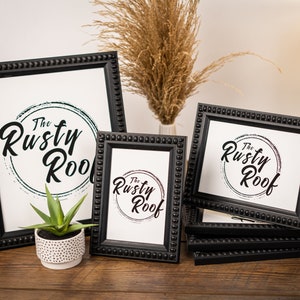 May include: Four black picture frames with beaded edges, each displaying a white print with the text "The Rusty Roof" in a circular design. The frames are stacked on top of each other, with the largest frame at the top and the smallest frame at the bottom.