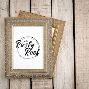 May include: A gold-colored ornate picture frame with a white background and the text "The Rusty Roof" in black lettering.