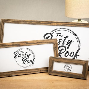 May include: Three wooden framed signs with the text "The Rusty Roof" in a circular design. The frames are stained a dark brown color. The signs are rectangular and vary in size, with a white background.