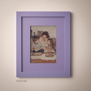 A framed photograph of a family, including a woman and two children, sitting together and looking at something on a table.