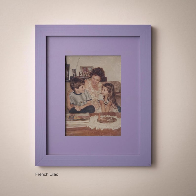 A framed photograph of a family, including a woman and two children, sitting together and looking at something on a table.