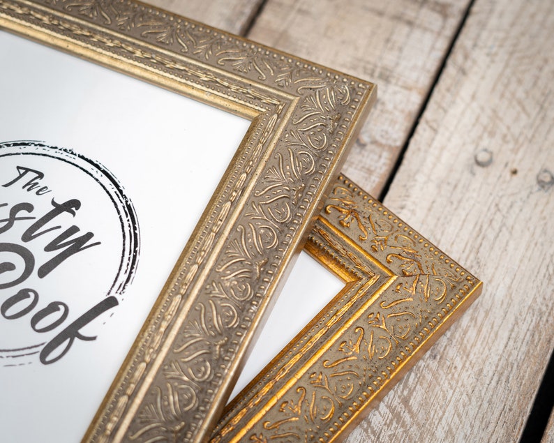 May include: Two ornate gold picture frames with a decorative, embossed design. The top frame has a white mat and a black and white logo that says "The Styl Nook".