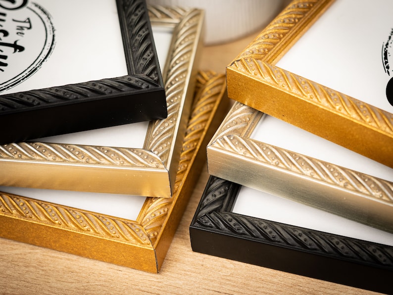 May include: Four picture frames in different colors, black, gold, silver, and black. The frames have a rope-like design around the edges.