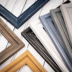 May include: A collection of wooden picture frames in various colors, including brown, gold, gray, white, and navy blue. The frames have a textured, weathered appearance, with visible wood grain. The frames are arranged at different angles, showcasing their corner details.