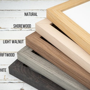 May include: Five different wood picture frames stacked on top of each other. The frames are in the following colors: natural, shorewood, light walnut, driftwood, and graphite.