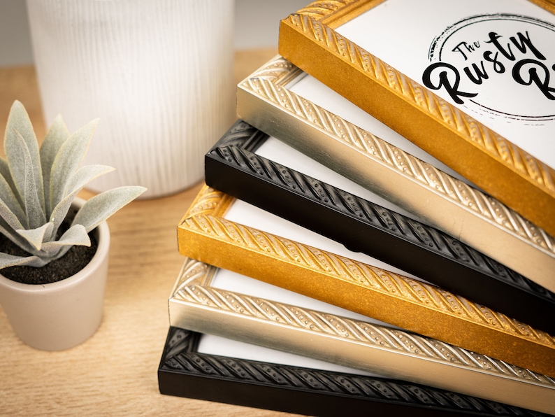 May include: A stack of four picture frames with ornate rope-like detailing. The frames are in black, silver, gold, and gold with a darker finish. The top frame has a white label with the text "The Rusty Pig".
