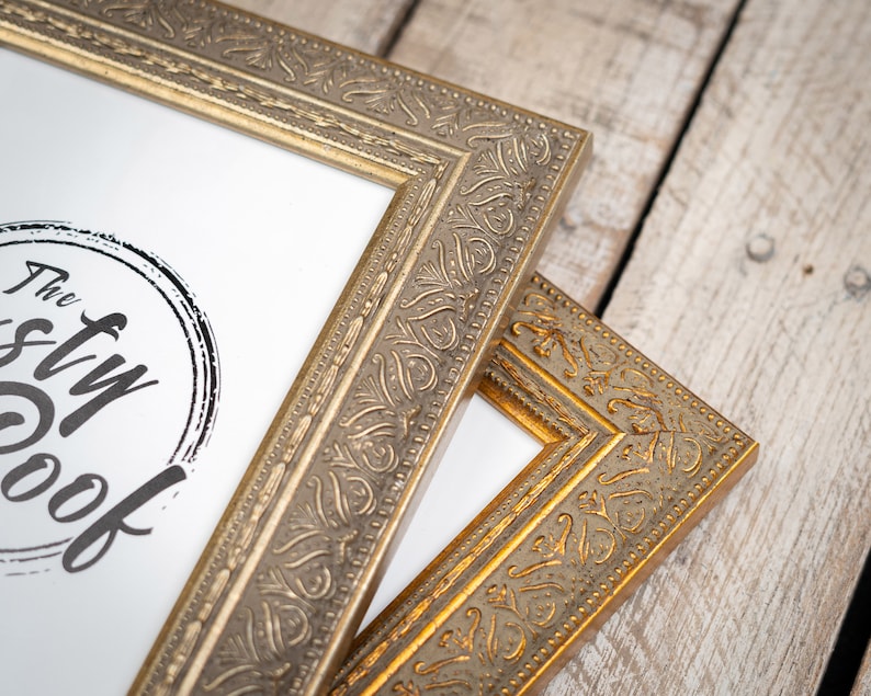 May include: Two ornate gold picture frames with a decorative, embossed design. The top frame has a white mat and a black and white logo that says "The Styl Nook".