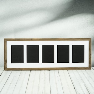 May include: A rectangular wooden picture frame with five openings. The frame has a light brown, rustic finish. Each opening contains a black background, surrounded by a white mat. The frame is displayed on a white wooden surface.