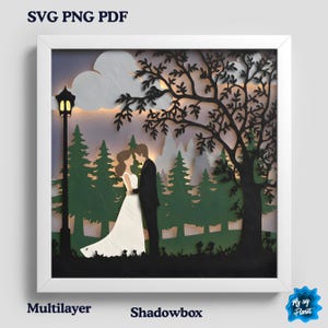 Puede incluir: Una obra de arte de caja de sombras multicapa que representa a una pareja abrazándose bajo un árbol. La escena incluye una farola, árboles y un cielo nublado. El texto "SVG PNG PDF" y "Multilayer Shadowbox" son visibles.