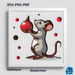 May include: A framed multilayer shadowbox art piece depicting a cartoon mouse holding a red Christmas bauble. The artwork includes red and brown circular accents against a white background. Text at the top reads "SVG PNG PDF".