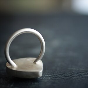 May include: A silver ring with a heart-shaped design. The ring is made of metal and has a smooth, polished finish.