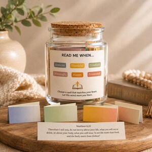 May include: A glass jar with a cork lid contains cards labelled "Read Me When..." with words such as "Anxious" and "Happy." The jar sits on a wooden board with additional cards and a Bible. A quote from Matthew 6:25 is also visible.