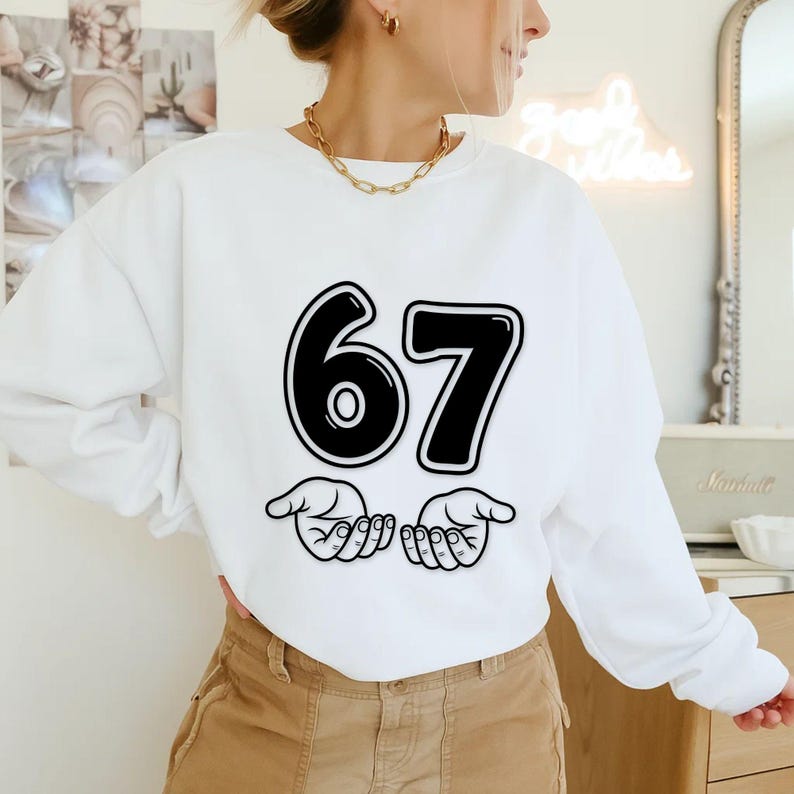 Pu&ograve; includere: Felpa bianca con il numero "67" in nero, bordato di bianco. Sotto i numeri ci sono due mani dei cartoni animati. La felpa &egrave; in stile casual, adatta all'uso quotidiano.