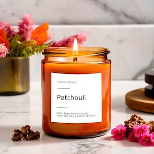 May include: An 8 oz. Patchouli scented candle in a clear glass jar with a lit wick. The candle has a white label with the text "VVAXYS CANDLES" and "Patchouli". The burn time is 40 hours and is made with soy wax and essential oils.