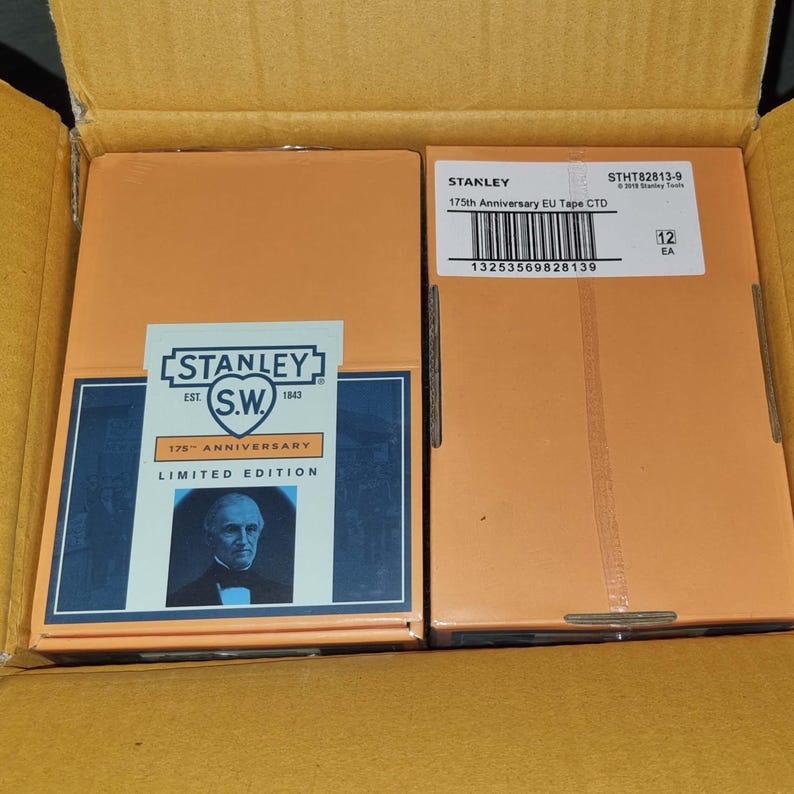 May include: Two orange boxes inside a cardboard box. The boxes are labeled "STANLEY 175th Anniversary EU Tape CTD Limited Edition". The boxes have a blue and white label with a portrait of a man.