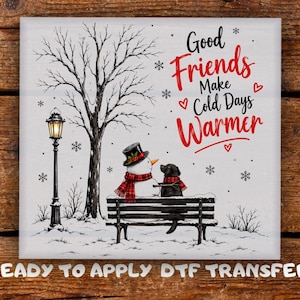 May include: A square DTF transfer featuring a winter scene with a snowman and a black dog sitting on a bench under a streetlamp. The text reads Good Friends Make Cold Days Warmer, accompanied by red hearts and snowflakes on a white background.